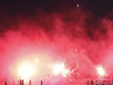 Pendukung PSS Sleman, Brigata Curva Sud menyalakan suar usai laga Piala Kemerdekaan menghadapi Persepam Madura United di Stadion Wilis, Madiun, Sabtu (15/08/2015). Persepam berhasil taklukan PSS 2-0. (Bola.com/Robby Firly)