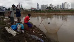 Beberapa warga tengah mencari ikan dengan menggunakan jala di Banjir Kanal Barat, Tanah abang, Jakarta, Sabtu (4/1/2020). Debit air yang mulai surut di aliran tersebut dimanfaatkan warga untuk mencari ikan. (Liputan6.com/Angga Yuniar)