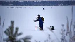 Seorang pria membuat lubang sebelum memulai memancing di tengah laut Bothnia yang sedang membeku di Vaasa, Finlandia, Rabu (27/12). Melalui lubang tersebut mereka memberikan umpannya kepada ikan buruan. (OLIVIER MORIN / AFP)