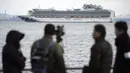 Seorang kru TV memfilmkan sebuah kapal pesiar Diamond Princess berlabuh di Pelabuhan Yokohama di Yokohama, Tokyo (4/2/2020). Otoritas Kesehatan Jepang mengkarantina 3.700 orang di dalam sebuah kapal pesiar setelah satu penumpang dinyatakan positif terkena virus corona.  (AP Photo/Eugene Hoshiko)