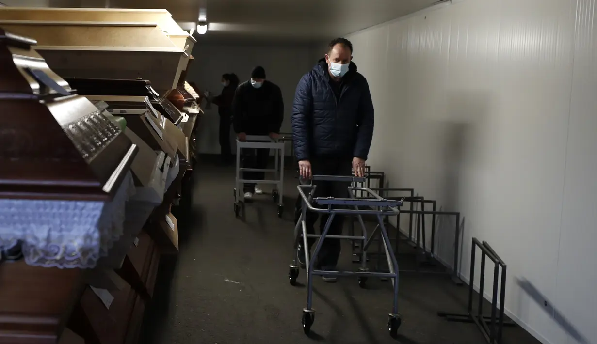 Pekerja berjalan melewati peti mati yang diletakkan di dalam peralatan pendingin yang melimpah di luar krematorium di Ostrava, Republik Ceko pada 7 Januari 2021. Krematorium terbesar di Republik Ceko telah kewalahan dengan meningkatnya jumlah korban pandemi virus corona Covid-19. (AP Photo/Petr Davi