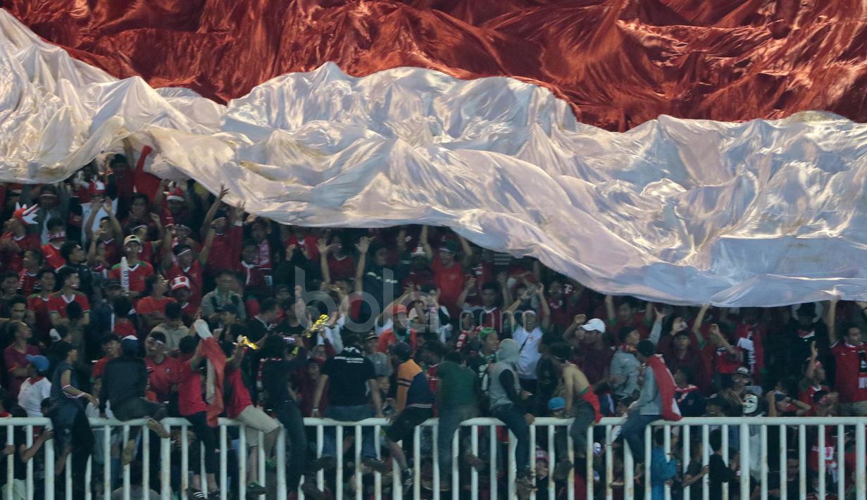 Suporter Timnas Indonesia mengibarkan bendera raksasa saat melawan Thailand pada laga Final Piala AFF 2016 di Stadion Pakansari, Bogor, (14/12/2016). (Bola.com/Nicklas Hanoatubun)