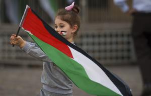 Seorang anak kecil mengibarkan bendera Palestina sebelum unjuk rasa pro-Palestina yang diikuti oleh ratusan orang, di pusat kota Bucharest, Rumania, Sabtu, 21 Oktober 2023. (AP Photo/Andreea Alexandru)