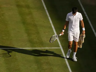 Petenis Serbia, Novak Djokovic berjalan di lapangan pada babak perempatfinal Wimbledon 2017 saat bertemu petenis Ceko, Tomas Berdych, Rabu (12/7). Djokovic memutuskan mundur setelah mengalami cedera siku saat menjalani pertandingan. (AP/Alastair Grant)