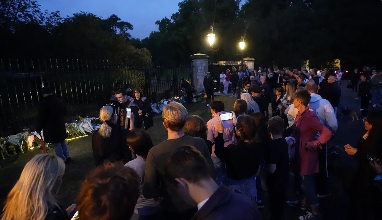 Para pelayat berkumpul menyusul pengumuman meninggalnya Ratu Elizabeth II di luar Kastil Windsor di Berkshire, Inggris, Kamis, 8 September 2022.  Sang ratu meninggal pada Kamis, 8 September 2022 petang waktu setempat atau Jumat (9/9/2022) dini hari Waktu Indonesia Bagian Barat (WIB). (Andrew Matthews/PA via AP)
