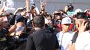 Lewis Hamilton dengan kawalan ketat pihak keamanan F1 melayani permintaan tanda tangan dari ratusan fans yang menanti di gerbang masuk arena Sirkuit Monza. (Bola.com/Reza Khomaini)