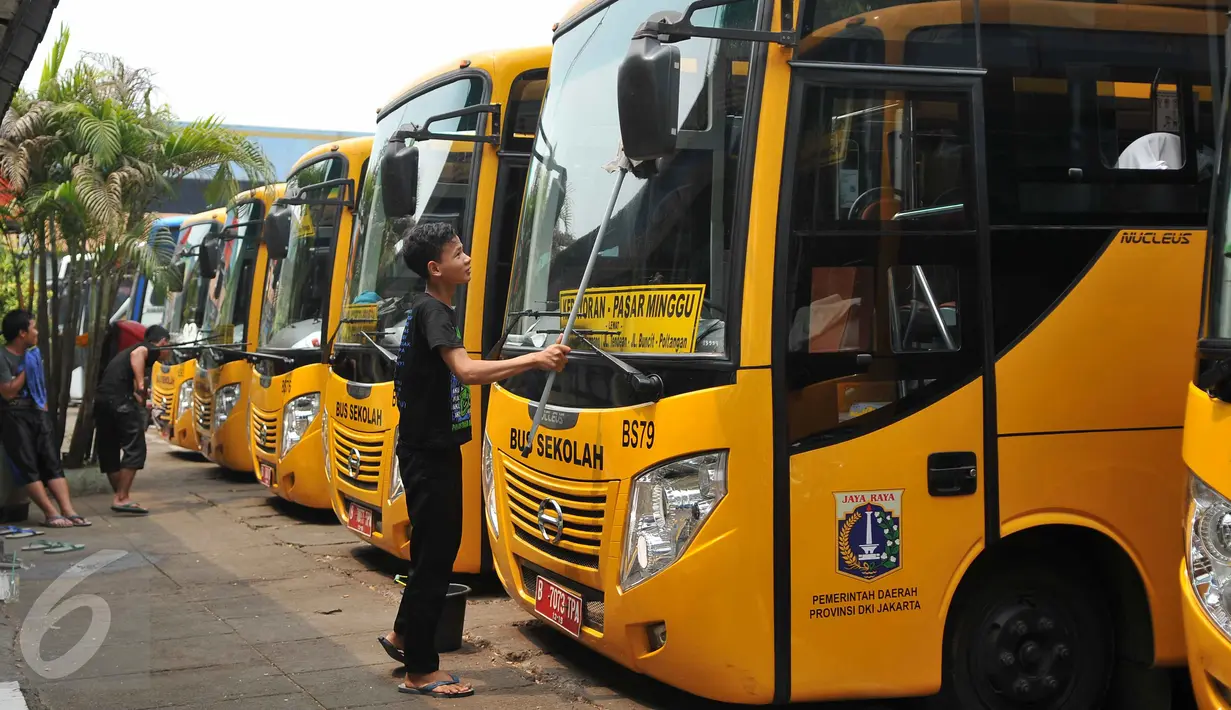 Petugas mengelap bus sekolah di Terminal Pasar Minggu, Jakarta, Senin (26/10). Gubernur DKI Basuki Tjahaja Purnama berencana menghapus keberadaan bus sekolah. Sebagai gantinya, pelajar akan digratiskan naik Transjakarta. (Liputan6.com/Gempur M Surya)