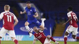 Striker Chelsea, Olivier Giroud (atas) melompat menghindari tekel bek Arsenal, Rob Holding dalam laga lanjutan Liga Inggris 2020/2021 pekan ke-35 di Stamford Bridge, London, Rabu (12/5/2021). Chelsea kalah 0-1 dari Arsenal. (AP/Adam Davy/Pool)