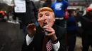Aksi penolakan Donald Trump sebagai Presiden AS di Washington DC, Jumat (20/1). Seorang demonstran memakai topeng berwajah mirip Trump dengan hidung yang dipanjangkan. (AFP PHOTO / Jewel SAMAD)