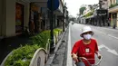 Seorang wanita mengendarai sepeda di sepanjang jalan yang hampir kosong di Hanoi pada hari pertama lockdown selama dua minggu, Sabtu (24/7/2021). Vietnam memberlakukan pembatasan yang lebih ketat di Hanoi mulai Sabtu (24/7), akibat gelombang infeksi COVID-19 terburuknya. (Manan VATSYAYANA / AFP)