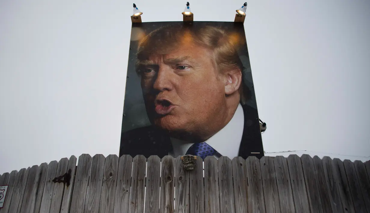 Sebuah baliho raksasa calon Presiden dari Partai Republik Donald Trump terpampang di halaman belakang rumah George Davey di West Des Moines, Iowa, (25/1/2016).  (AFP/JIM WATSON)