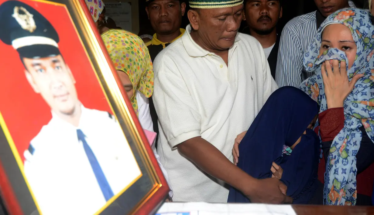 Istri (kanan) dan anak menyambut kedatangan jenazah Yudhistira Febbi Arianto, co pilot pesawat Aviastar di masjid dekat Bandara Ngurah rai, Bali, Kamis (8/10). Pesawat Aviastar jatuh dan menewaskan 3 kru dan 7 penumpang. (AFP PHOTO/SONNY TUMBELAKA)