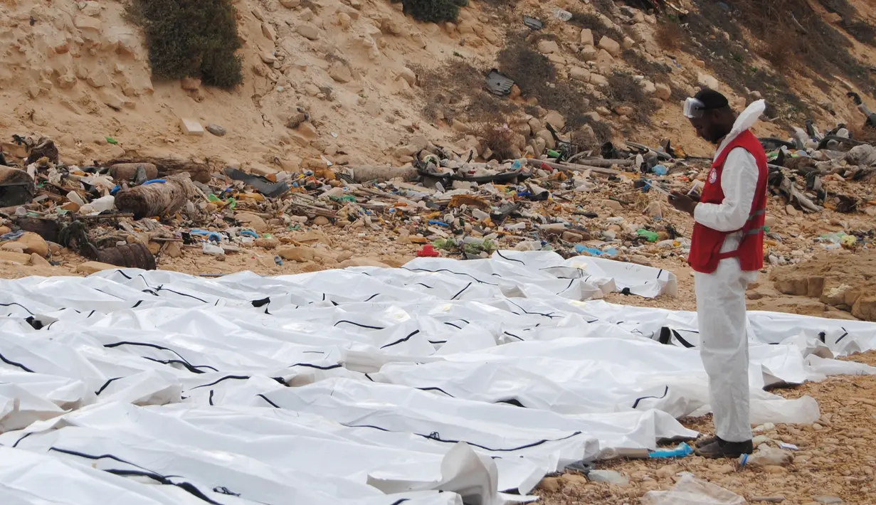 Puluhan jenazah imigran dalam kantong mayat berwarna putih tergeletak di pantai utara Libya, Selasa (21/2). Petugas Bulan Sabit Merah Libya juga mennemukan sebuah perahu karet yang robek di sekitar pantai. (MOHANED KREMA/AFP)