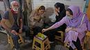 Pemilik Kazem Mabhutian (kiri) minum teh dengan pelanggannya di luar kedai teh terkecil dan tertua yang terletak di gang Grand Bazaar di ibukota Iran, Teheran (20/9/2021). (AFP/Atta Kenare)