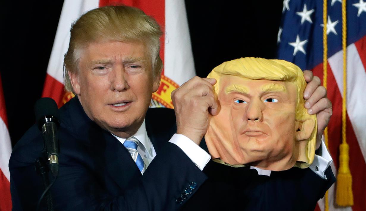 Ekspresi Donald Trump saat menunjukan topeng wajah dirinya ke awak media saat berkampanye di Sarasota, Florida, AS (7/11). Pilpres AS 2016 akan diadakan pada 8 November 2016 dan menjadi pilpres empat tahunan ke-58.  (REUTERS/Carlo Allegri) 
