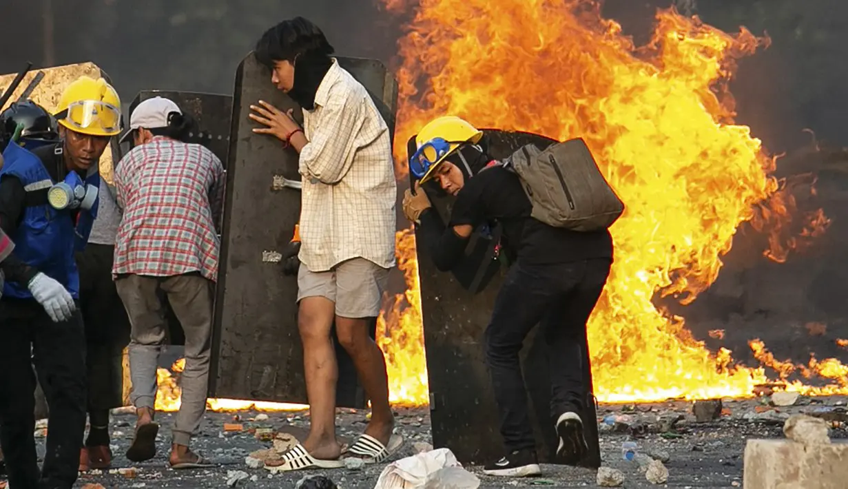 Para pengunjuk rasa berlindung di balik perisai buatan sendiri saat mereka menghadapi polisi selama tindakan keras terhadap demonstrasi menentang kudeta militer di Yangon, Myanmar, 16 Maret 2021. (STR/AFP)