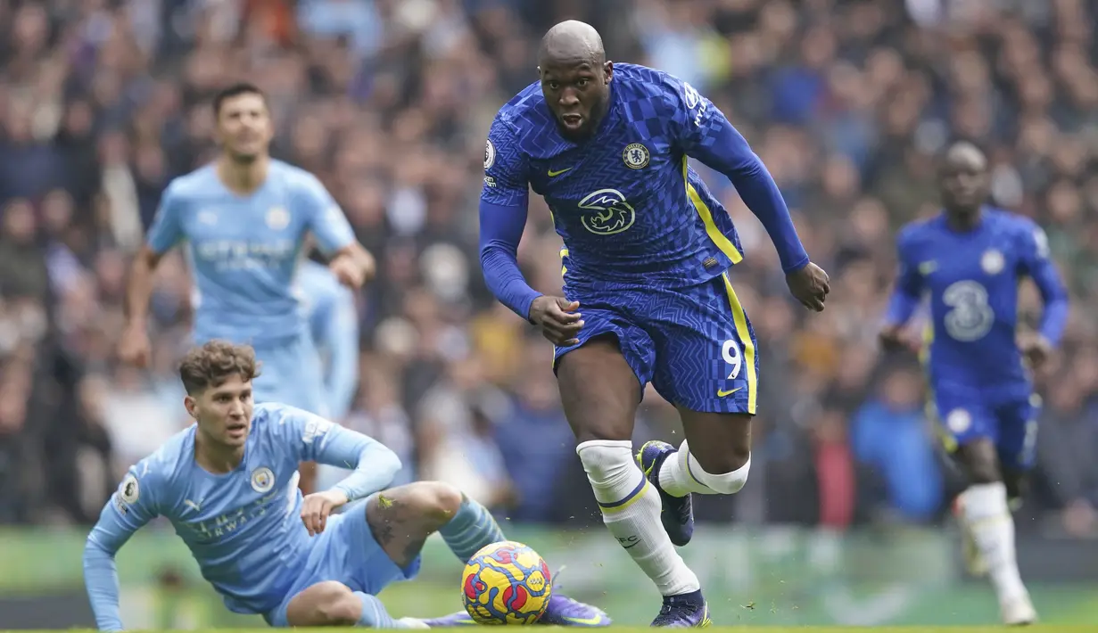 Penyerang Chelsea, Romelu Lukaku (tengah) membawa bola melewati bek Manchester City, John Stones saat pertandingan Liga Inggris di stadion Etihad, Sabtu (15/1/2022). Hasil ini membuat Man City unggul 13 poin atas Chelsea yang menempati peringkat dua di klasemen. (AP Photo/Dave Thompson)