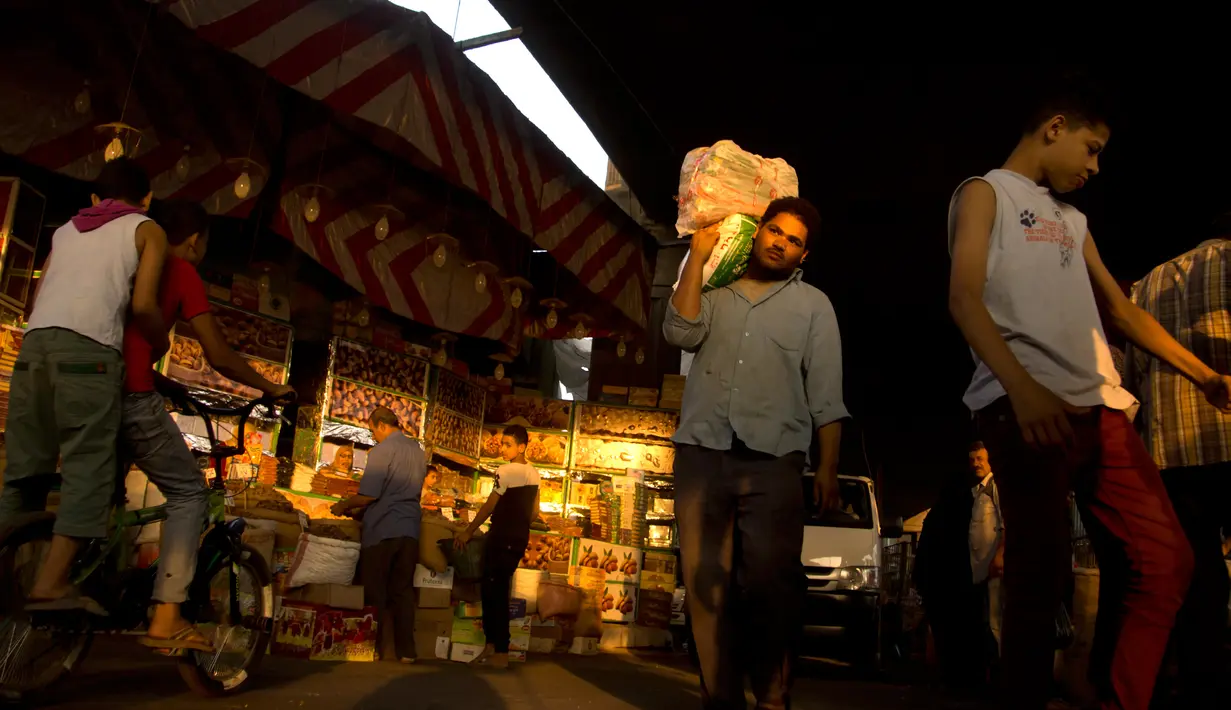 Seorang pria membawa barang belanjaannya di sebuah pasar di Kairo, Mesir (24/5). Umat muslim di seluruh dunia bersiap untuk merayakan datangnya bulan suci Ramadan. (AP Photo / Amr Nabil)