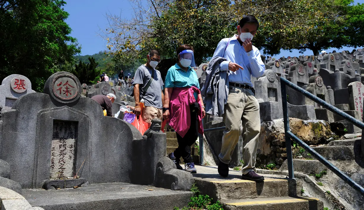 Sebuah keluarga berjalan melewati pemakaman saat Festival Ching Ming atau Hari Sapu Makam di Hong Kong, Selasa (5/4/2022). Ribuan warga Hong Kong memberi hormat kepada leluhur dan kerabat mereka selama festival tahunan ini. (AP Photo/Vincent Yu)