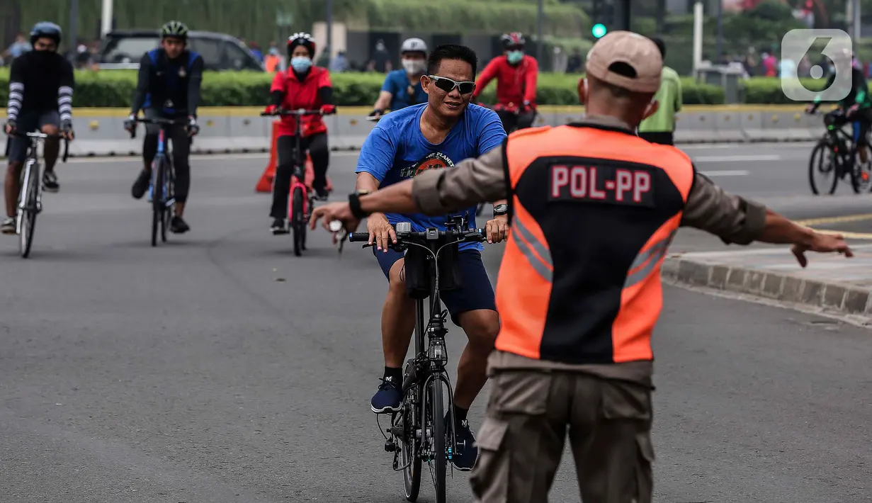 Satpol PP menghentikan pesepeda yang tidak mengenakan masker saat melintas di kawasan Bundaran HI, Jakarta, Minggu (17/1/2021). Pemerintah terus melakukan berbagai upaya guna mencegah penyebaran COVID-19 dan menurunkan angka masyarakat yang terpapar virus corona. (Liputan6.com/Johan Tallo)