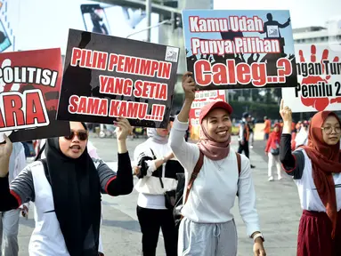 Sejumlah warga membawa poster bertuliskan sosialisasi Pemilu 2024, saat Hari Bebas Kendaraan Bermotor (HBKB) di kawasan Bundaran HI, Jakarta, Minggu (20/8/2023). (Liputan6.com/Johan Tallo)