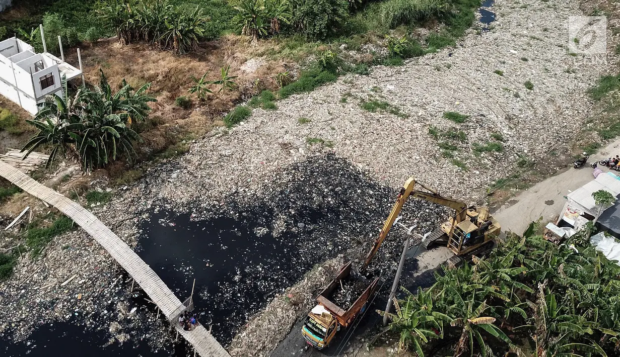 Pantauan dari udara, alat berat mengeruk sampah yang menutupi Kali Pisang Batu, Tarumajaya, Bekasi, Rabu (9/1). Sampah rumah tangga yang diduga dari aliran kali di wilayah Kota Bekasi  dikeluhkan warga karena bau tidak sedap. (Liputan6.com/Fery Pradolo)