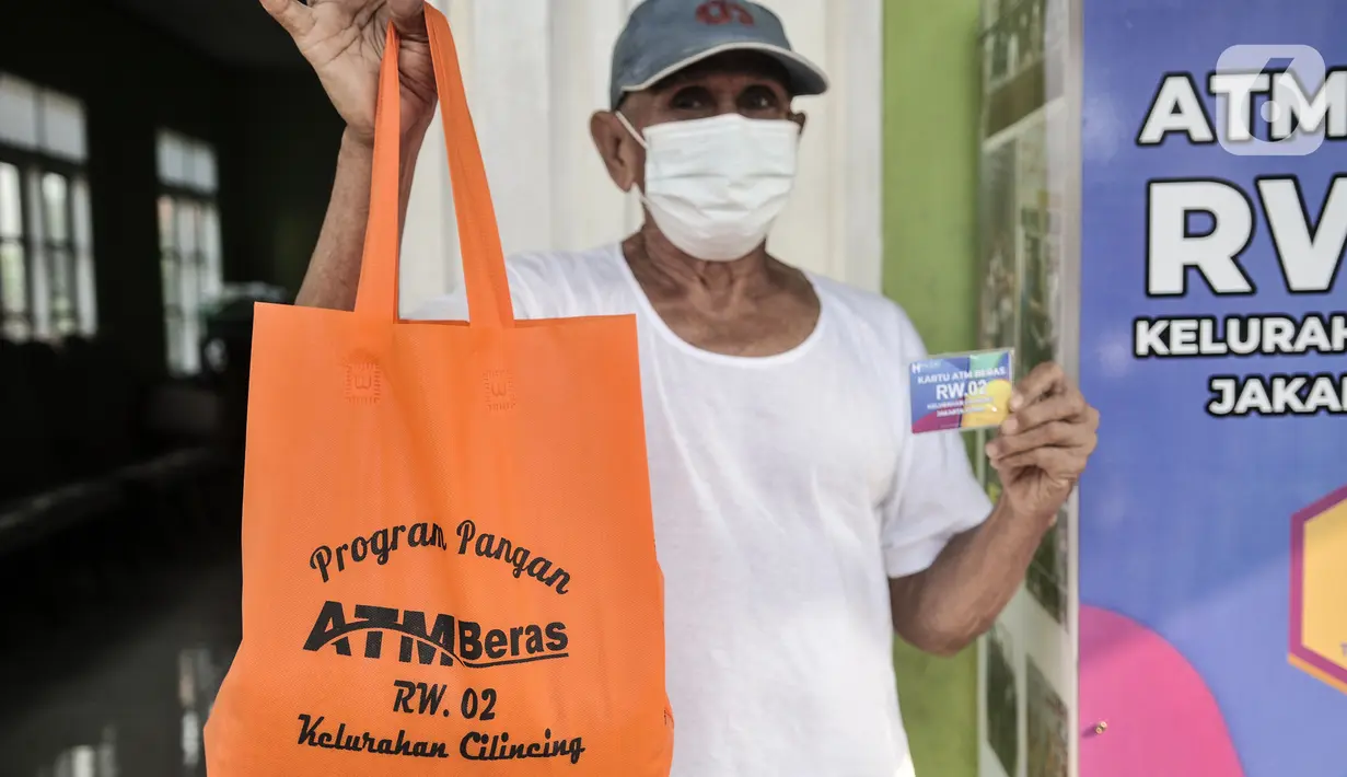 Warga menunjukkan kartu ATM dan paket bantuan beras di Kantor RW 02, Kelurahan Cilincing, Jakarta Utara, Rabu (17/3/2021).  Pembuatan ATM Beras secara mandiri sebagai program ketahanan pangan di masa pandemi Covid-19. (merdeka.com/Iqbal S. Nugroho)