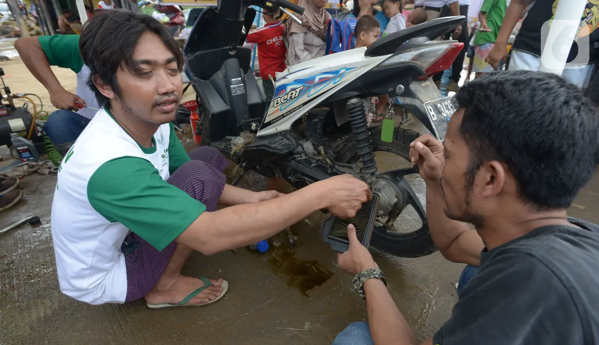 Relawan memperbaiki sepeda motor korban banjir pada layanan bengkel gratis Badan Amil Zakat Nasional (BAZNAS) di Kampung Pulo, Jakarta, Sabtu (4/1/2020). Layanan bengkel gratis ini banyak dimanfaatkan korban banjir untuk memperbaiki sepeda motornya yang sempat terendam. (merdeka.com/Imam Buhori)