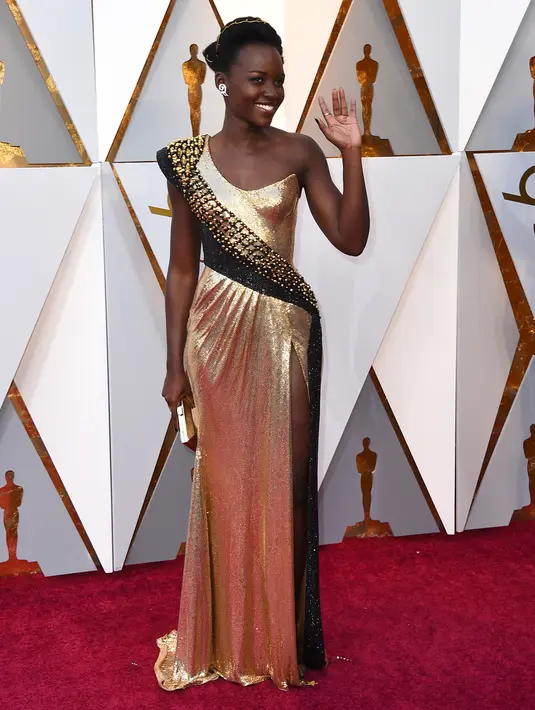 Aktris Lupita Nyong'o berpose di karpet merah ajang Piala Oscar 2018, Los Angeles, Minggu (4/3). Pemeran Nakia dari Black Phanter ini tampil mewah dalam balutan dress emas-hitam berkilau dari Atelier Versace. (Jordan Strauss/Invision/AP)