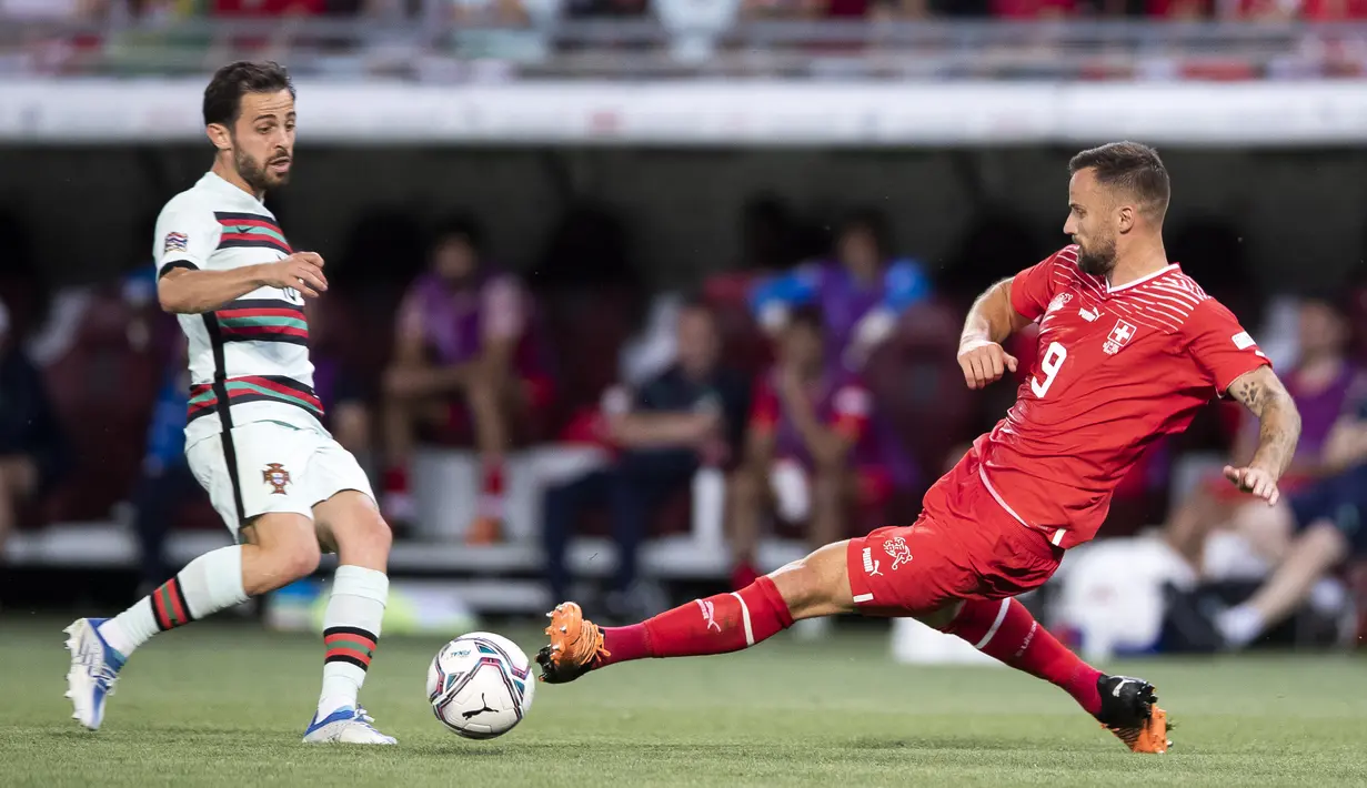 Pemain Portugal Bernardo Silva (kiri) berebut bola dengan pemain Swiss Haris Seferovic (kanan) pada pertandingan sepak bola Grup A2 UEFA Nations League di Stadion Stade de Geneve, Jenewa, Swiss, 12 Juni 2022. Portugal kalah tipis 0-1 dari Swiss. (Cyril Zingaro/Keystone via AP)