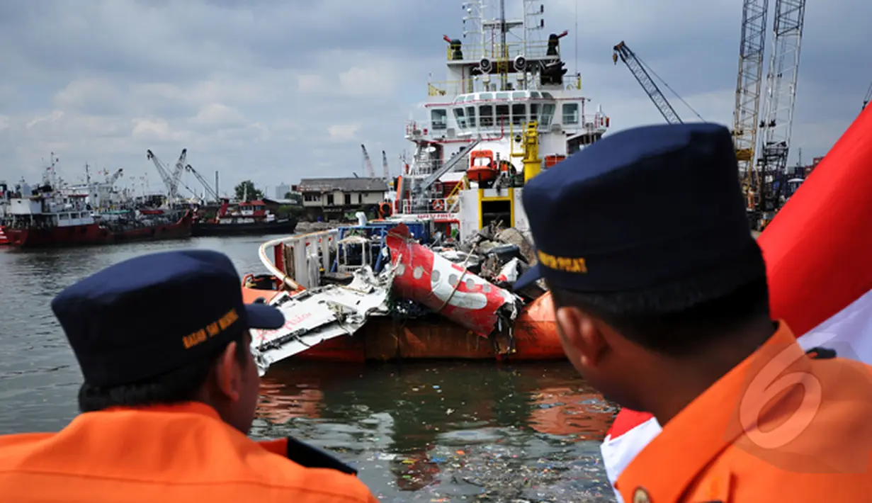 Dua orang petugas Basarnas memperhatikan kondisi bangkai badan pesawat Airasia QZ8501 yang berhasil dievakuasi, Pelabuhan Tanjung Priok, Jakarta, Senin (2/3/2015). (Liputan6.com/Faizal Fanani)