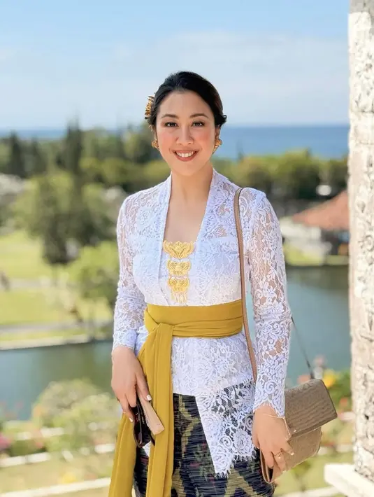 Siluetnya ramping namun tetap nyaman, memperlihatkan detail artistik yang begitu halus. Dipadukan dengan kamen motif khas Bali dan selendang kuning kunyit yang diikat anggun di pinggang, tampilannya terasa begitu otentik sekaligus elegan. [@sherinamunaf].