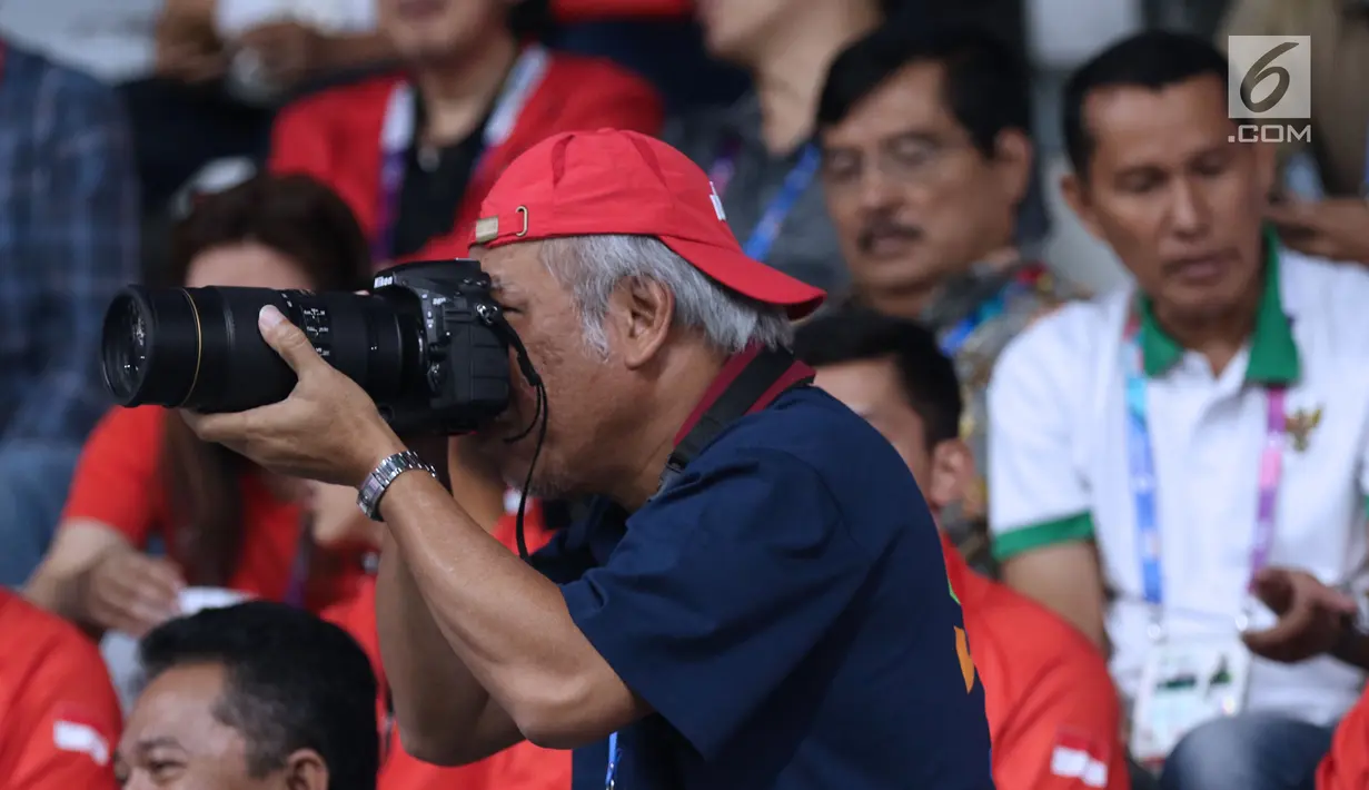 Menteri PUPR, Basuki Hadimuljono terlihat mengabadikan momen saat laga semifinal bulu tangkis beregu putra Asian Games 2018, Indonesia melawan Jepang di Jakarta, Selasa (21/8). Indonesia unggul dan lolos ke final. (Liputan6.com/Helmi Fithriansyah)