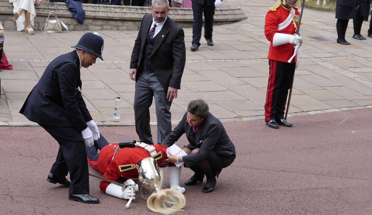 Seorang prajurit yang pingsan mendapat pertolongan segera jelang kebaktian Order of the Garter di Windsor Castle, di Windsor, Inggris, Senin, 19 Juni 2023. Order of the Garter adalah Order of Chivalry tertua dan paling senior di Inggris, yang didirikan oleh Raja Edward III hampir 700 tahun yang lalu.(AP Photo/Kirsty Wigglesworth, Pool)