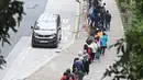 Orang-orang mengantre di stasiun pengumpulan spesimen bergerak untuk pengujian Covid-19 di distrik Tung Chung, Hong Kong pada 10 Februari 2022. Antrean terjadi ketika pihak berwenang bergegas untuk meningkatkan kapasitas pengujian menyusul rekor jumlah infeksi baru yang tinggi. (Peter PARKS / AFP)