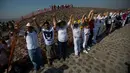 Wisatawan mengangkat tangan merasakan hangatnya sinar mentari pada upacara menyambut fenomena equinox di depan Piramida Matahari, Teotihuacan, Meksiko, Senin (20/3). Equinox terjadi dua kali dalam setahun, yakni Maret dan September. (AP/Rebecca Blackwell)
