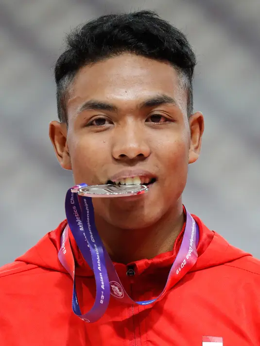 Sprinter Indonesia, Lalu Muhammad Zohri menggigit medali usai mengikuti kategori 100 meter dalam Kejuaraan Atletik Asia di Doha, Qatar, Senin (22/4). Zohri merebut medali perak dengan catatan waktu 10,13 detik yang juga memecahkan rekor pelari tercepat Asia Tenggara, Suryo Agung. (AP/Vincent Thian)