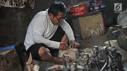 Perajin Oman Sumarna menyelesaikan pembuatan patung di Sanggar Primitif, Sawangan, Depok, Jawa Barat, Rabu (9/1). Harga patung-patung buatan Oman itu dijual dengan harga bervariasi tergantung tingkat kesulitan pembuatannya. (Liputan6.com/Herman Zakharia)