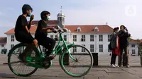 Anak-anak mengenakan masker menggunakan sepeda wisata di kawasan Kota Tua Jakarta, Kamis (29/10/2020). Libur panjang di masa pemberlakuan PSBB transisi Jakarta dimanfaatkan warga untuk mengunjungi lokasi-lokasi wiisata. (Liputan6.com/Helmi Fithriansyah)