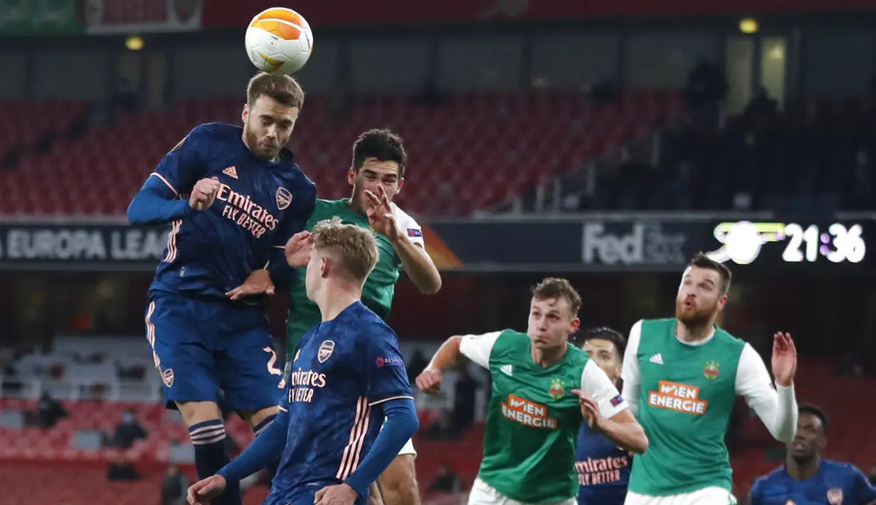 Pemain Arsenal Calum Chambers (kiri) menyundul bola saat melawan Rapid Wien pada pertandingan Grup B Liga Europa di Emirates Stadium, London, Inggris, Kamis (3/12/2020). Arsenal menyegel status juara Grup B Liga Europa usai menaklukkan Rapid Wien 4-1. (AP Photo/Frank Augstein)