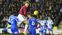 Scott McTominay dari Manchester United, kedua dari kiri, menyundul bola di depan Charlie Hughes dari Wigan Athletic saat pertandingan sepak bola putaran ketiga Piala FA Inggris antara Wigan Athletic dan Manchester United di DW Stadium, Wigan, Inggris, Senin, 8 Januari 2024. ( Foto AP/Jon Super)