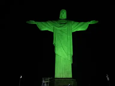 Patung Kristus Penebus raksasa yang terkenal di Rio de Janeiro, Brasil, diterangi dengan lampu hijau pada kesempatan Hari Lingkungan Hidup Sedunia pada Senin (5/6/2023). (CARL DE SOUZA / AFP)