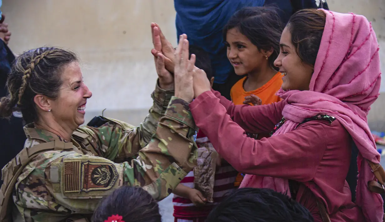 Seorang Penerbang AS dengan Satuan Tugas Gabungan-Respons Krisis melakukan tos dengan seorang anak setelah membantu menyatukan kembali keluarga mereka di Bandara Internasional Hamid Karzai di Kabul, Afghanistan, Jumat (20/8/2021).  (Cpl. Davis Harris/U.S. Marine Corps via AP)