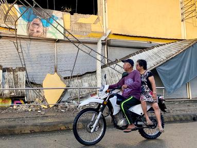 Sebuah sepeda motor melewati toko kelontong yang rusak sebagian akibat gempa di Kota Bayugan, Agusan del Sur, Filipina, Minggu (3/12/2023). Gempa bumi lepas pantai berkekuatan magnitudo 7,4 -- sebelumnya diberitakan sejumlah media bermagnitudo 7,5 dan 7,6 --  yang melanda Filipina selatan pada 2 Desember 2023 malam telah menewaskan satu orang dan melukai dua lainnya, lapor Xinhua pada Minggu (3/12/2023) mengutip otoritas setempat. (AP Photo/Ivy Marie Mangadlao)