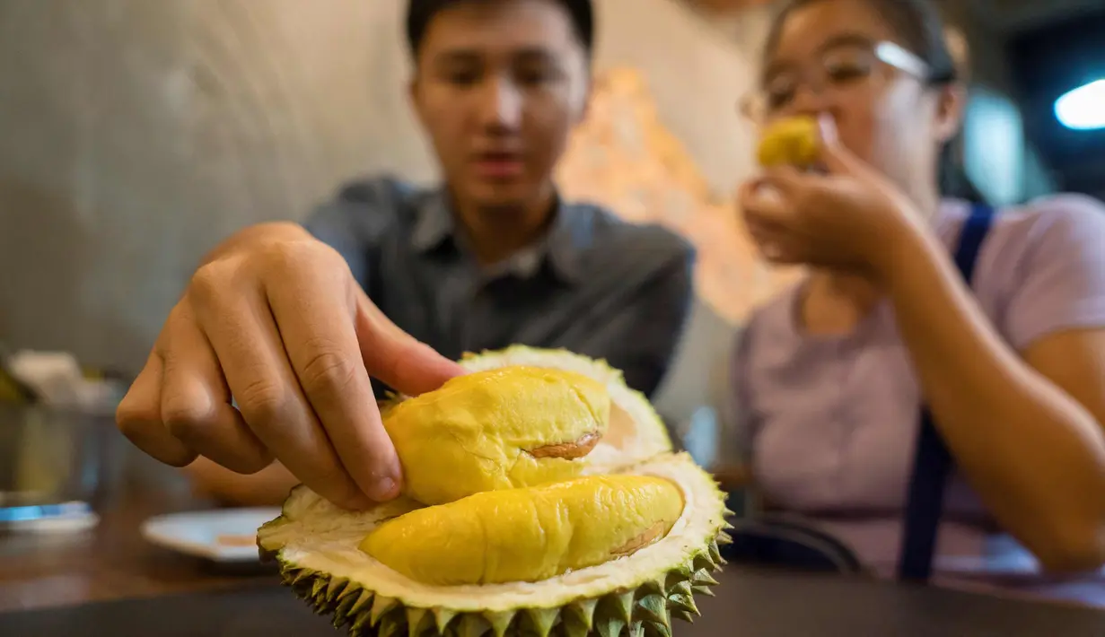 Pengunjung memakan durian di kafe Mao Shan Wang di Singapura (26/1). Restoran yang menyediakan beragam aneka rasa durian ini telah menarik banyak pengunjung untuk datang mencicipi buah durian di kafe tersebut. (AFP Photo/Nicholas Yeo)