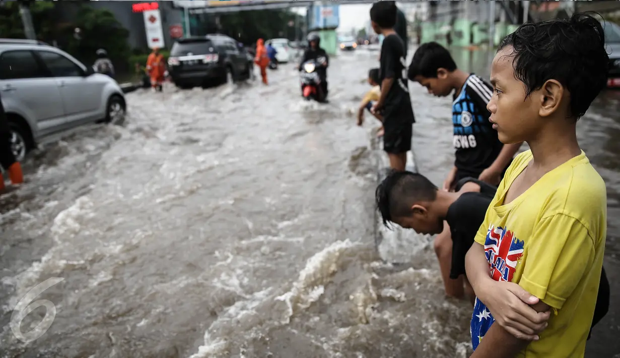 Sejumlah anak bermain di lokasi banjir yang menggenangi jalan di depan Ancol, Jakarta, Kamis (21/4). Hujan deras yang mengguyur sejak semalam menyebabkan beberapa kawasan di Jakarta tergenang banjir. (Liputan6.com/Faizal Fanani)