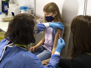 Seorang gadis menerima suntikan dosis pertama vaksin corona COVID-19 di Wina, Austria, Senin (15/11/2021). Pihak berwenang mulai hari Senin memvaksinasi anak-anak berusia antara 5 dan 11 tahun di ibu kota. (JOE KLAMAR / AFP)