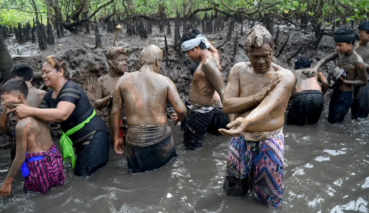 Orang-orang mengambil bagian dalam tradisi mandi lumpur yang dikenal sebagai Mebuug-buugan di Desa Kedonganan, Bali, 4 Maret 2022. Mebuug-buugan diadakan sehari setelah Nyepi yang bertujuan untuk menetralkan sifat buruk. (SONY TUMBELAKA/AFP)