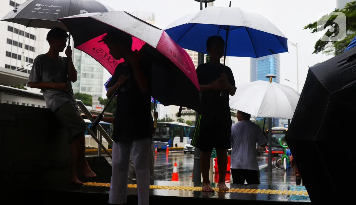 Anak-anak menawarkan jasa ojek payung di tengah hujan yang turun di kawasan Bundaran HI, Jakarta, Senin (3/2/2020). Hujan deras yang mengguyur sejumlah wilayah di DKI Jakarta dimanfaatkan para pengojek payung untuk mencari penghasilan tambahan. (Liputan6.com/Angga Yuniar)