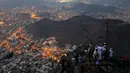 Para umat muslim berada di puncak Jabal Nur dengan pemandangan Kota Suci Mekah yang diterangi cahaya lampu saat malam hari ketika berziarah dan berdoa menjelang perayaan haji Idul Adha di Mekkah, Arab Saudi (7/9). (Reuters/Ahmed Jadallah)